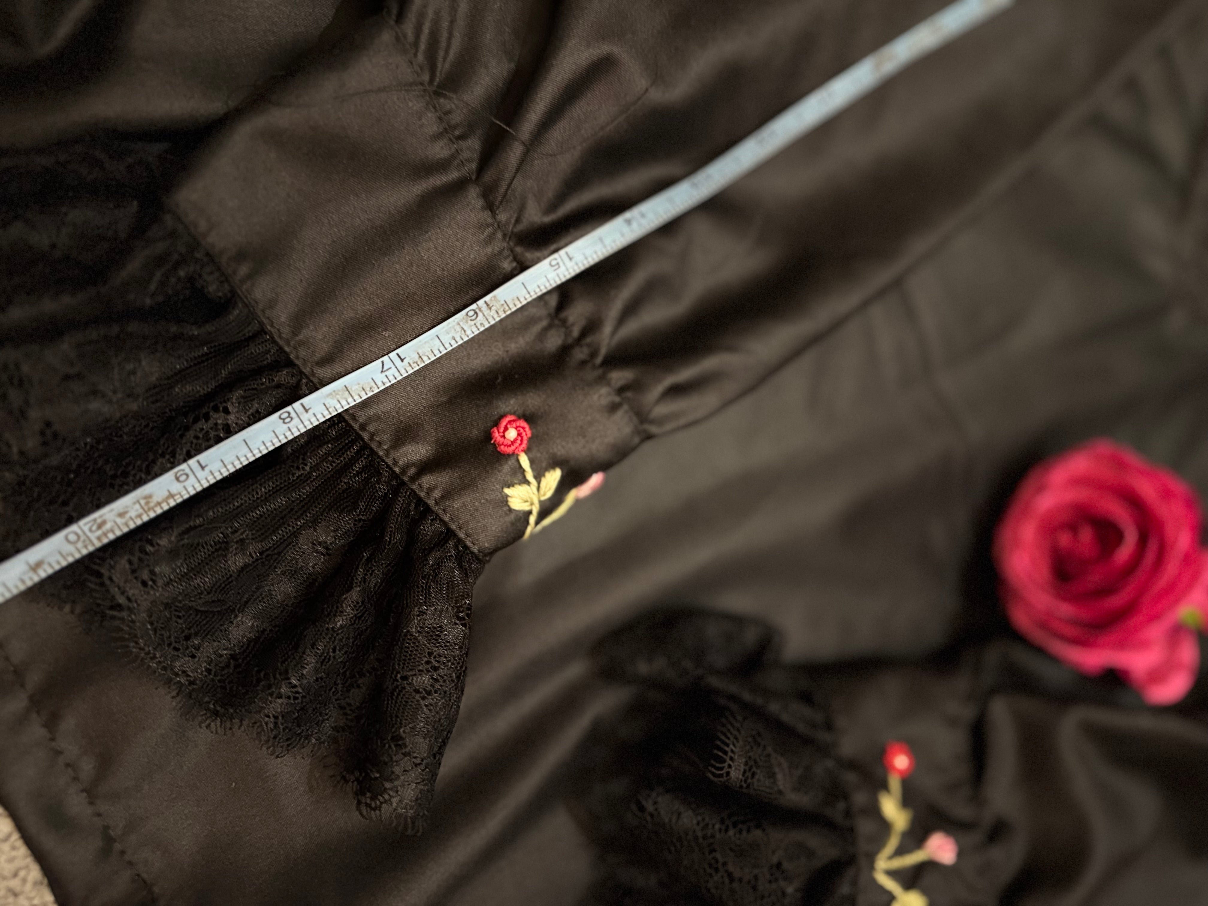 Close-up of black fabric with floral embroidery and a measuring tape.
